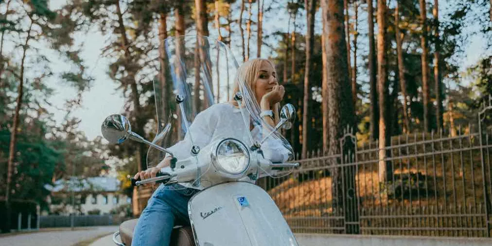Jonge vrouw op haar scooter langs de weg, net geslaagd voor haar scooterrijbewijs